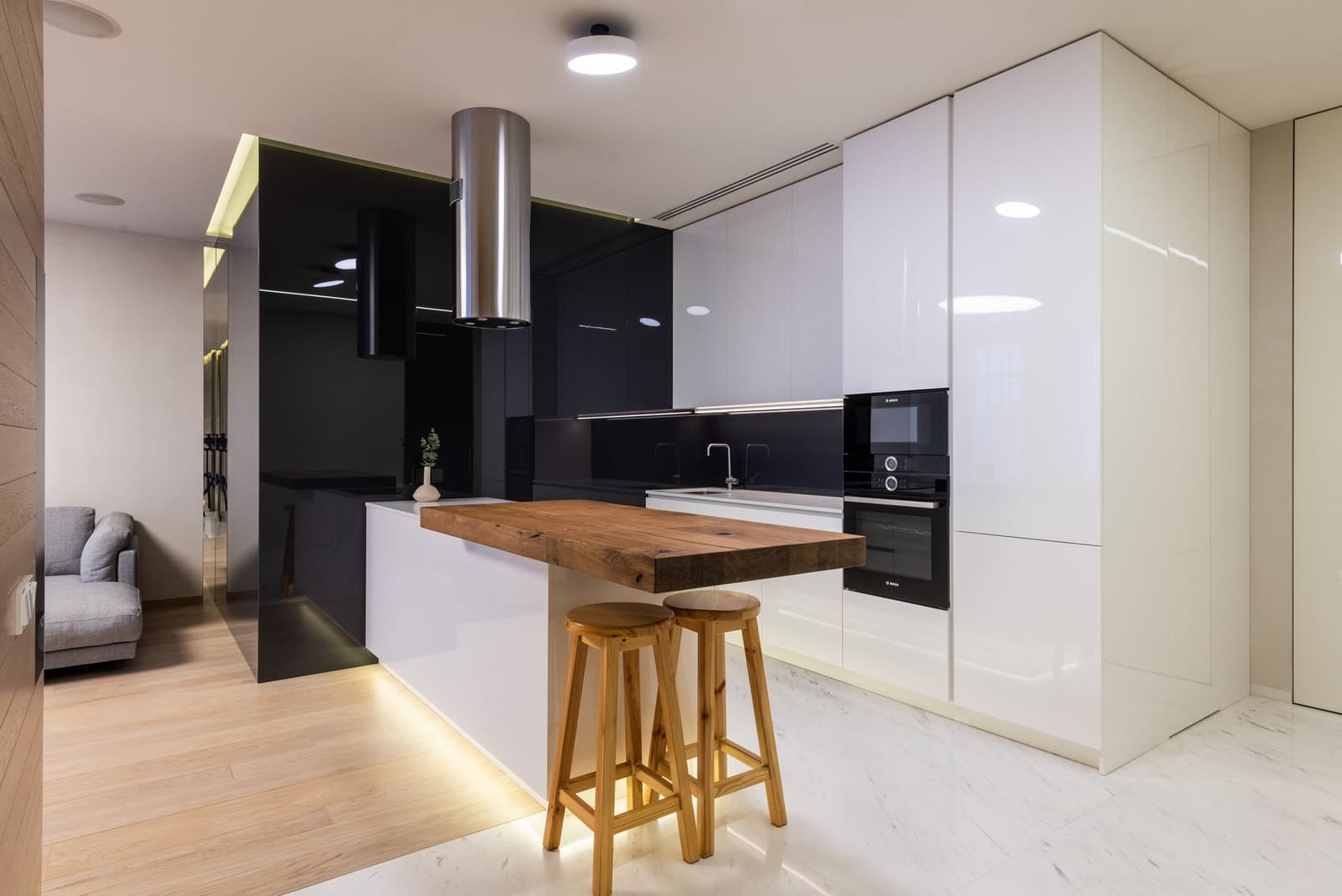 Cocina blanca y negra con isla de madera y taburetes