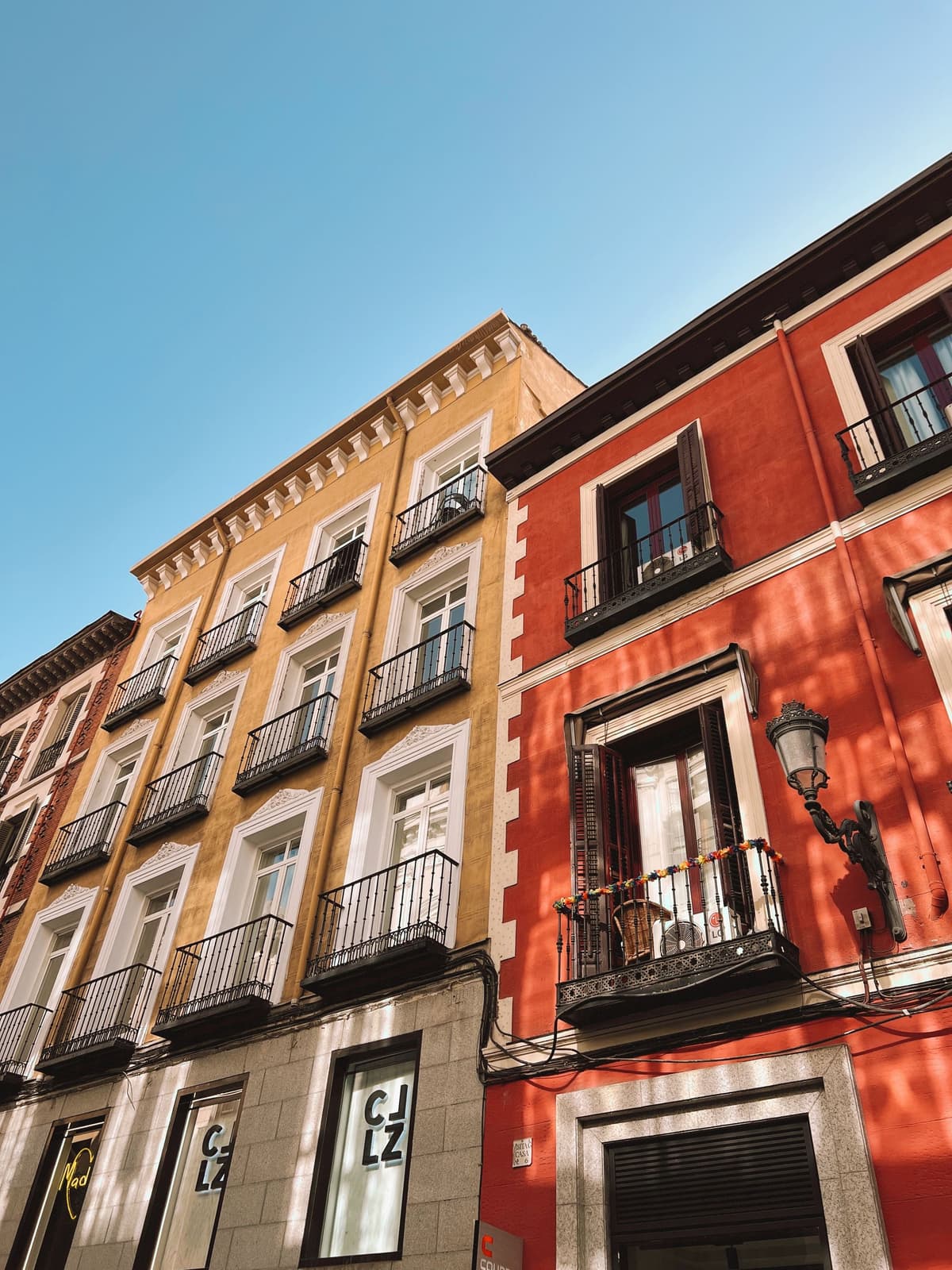Fachadas amarilla y roja con balcones de hierro